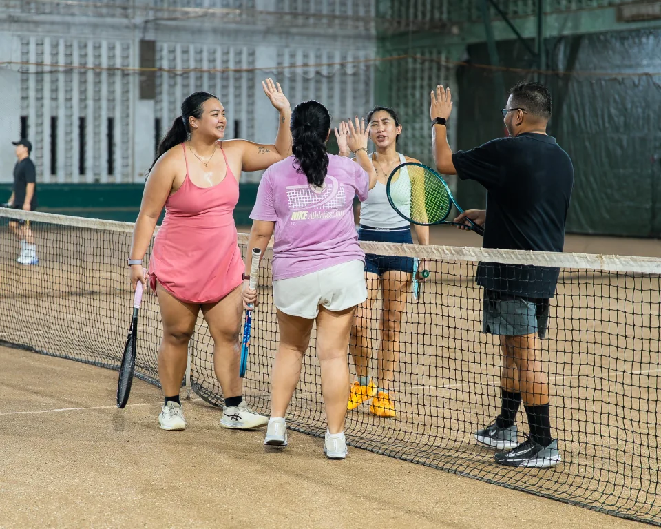 Players high-fiving at the net after a doubles match